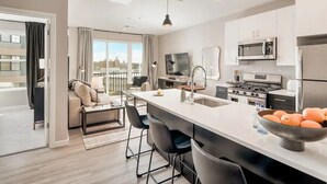 Una cocina moderna con una isla central, electrodomésticos de acero inoxidable y un amplio ventanal con vistas a la ciudad.