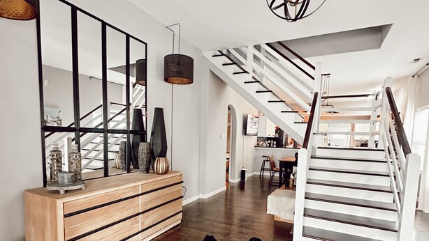 A modern interior with a staircase, wooden console, and a black leather rug. - Hot Tub Beautiful Downtown Indy Home! (Indianapolis)