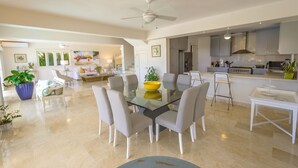 A spacious living area with a glass dining table surrounded by chairs, a kitchen with modern appliances, and a ceiling fan. - Private Villa with Pool and Golf Cart (San Rafael del Yuma)