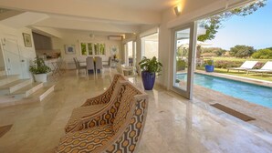 A spacious living area with a pool, a dining area, and a staircase leading to the upper floor. - Private Villa with Pool and Golf Cart (San Rafael del Yuma)