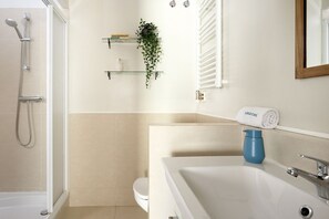 A modern bathroom with a shower, toilet, and a large bathtub. There are shelves with toiletries and a potted plant. - Casa Cosi - Casanova 1 (Barcelona)