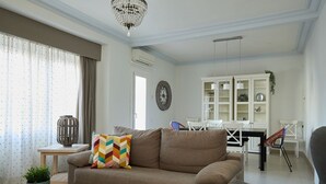 A living room with a sofa, a round table, a chandelier, a dining area with chairs, and a cabinet. - Casa Cosi - Casanova 4 (Barcelona)