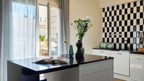 A modern kitchen with a black and white checkered backsplash, a black countertop, and a vase with flowers on the island. - Casa Cosi - Terrace 1 (Barcelona)