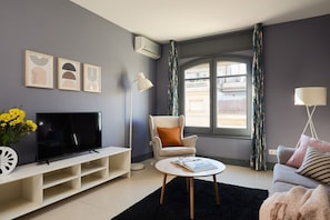 Ein modernes Wohnzimmer mit Flachbildfernseher, rundem Couchtisch und bequemem Sessel.