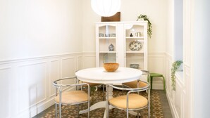 Un coin repas avec une table ronde et quatre chaises, un buffet contenant de la vaisselle et un sol à motifs.