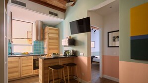 Una cucina moderna con mobili in legno, un angolo con uno sgabello da bar e un televisore a schermo piatto montato a parete.