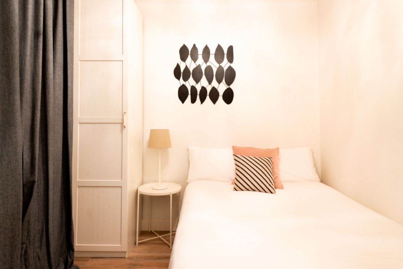 A hotel room with a bed, a nightstand, a lamp, and a wall decoration.