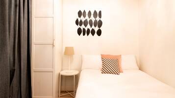 A hotel room with a bed, a nightstand, a lamp, and a wall decoration.