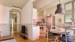 A modern kitchen with white cabinets, a central island, and a dining area with a round table and chairs.