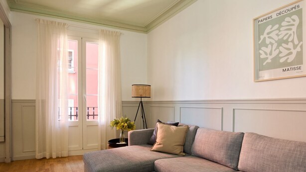 A living room with a grey sectional sofa, a floor lamp, and a framed artwork on the wall.