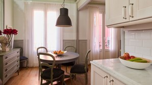 A kitchen with a round dining table, chairs, a hanging light fixture, and cabinets.