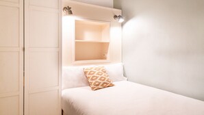 Un dormitorio con una cama, una mesita de noche y un estante en la pared.