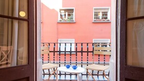 Un balcón con dos sillas de madera y una mesa redonda pequeña, cada uno con un cuenco azul.