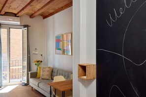 Un salón acogedor con un sofá, una mesa de madera y una pared de pizarra con la palabra 'welcome' escrita.