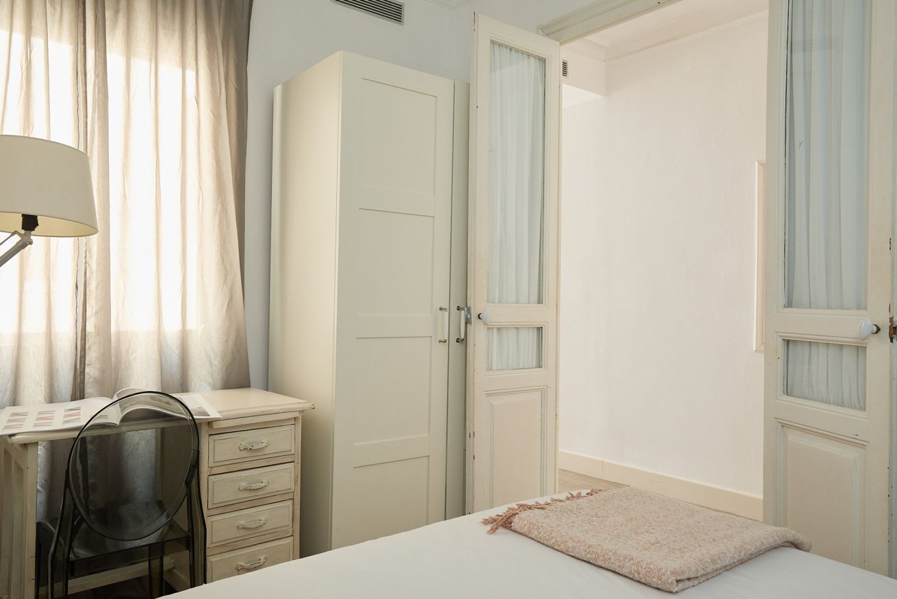 Una camera da letto con un letto, una scrivania con una sedia e un armadio.