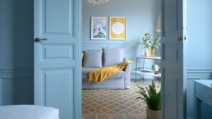 A room with a grey sofa, a yellow throw blanket, a globe, and a plant on a patterned floor.