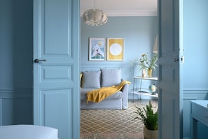 Una habitación con un sofá gris, una manta amarilla, un globo terráqueo y una planta sobre un piso estampado.
