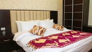 A neatly made bed with white linens, two patterned pillows, and a red and beige blanket. - Happy Family Apartment  (Wadi mousa)