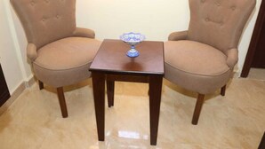 Two brown upholstered chairs with a square wooden table between them, featuring a decorative blue and white object on the table. - Happy Family Apartment  (Wadi mousa)