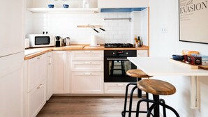 Una cocina moderna con armarios blancos, encimera de madera, estufa y un taburete de bar.