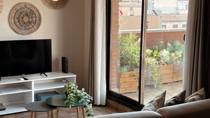 Una sala de estar moderna con un televisor de pantalla plana, una mesita con una planta y un sofá.