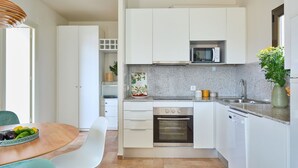 Una cocina moderna con armarios blancos, microondas, horno y lavavajillas.
