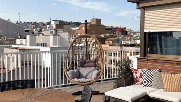 Una terraza en la azotea con una silla colgante, un sofá y una mesa.