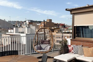 A rooftop terrace with a hanging chair, a sofa, and a table. - Casa Cosi - Industria (Barcelona)