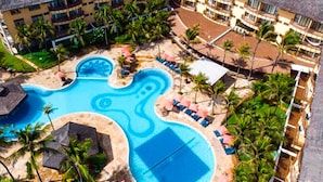 Un resort con una amplia piscina, palmeras y tumbonas.