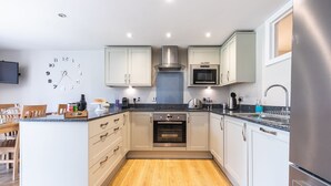 Eine moderne Küche mit weißen Schränken, einem eingebauten Backofen, einer Mikrowelle und einem Edelstahl-Kühlschrank.
