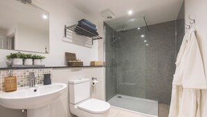 Ein modernes Badezimmer mit Duschkabine aus Glas, Toilette, Waschbecken und Spiegel.