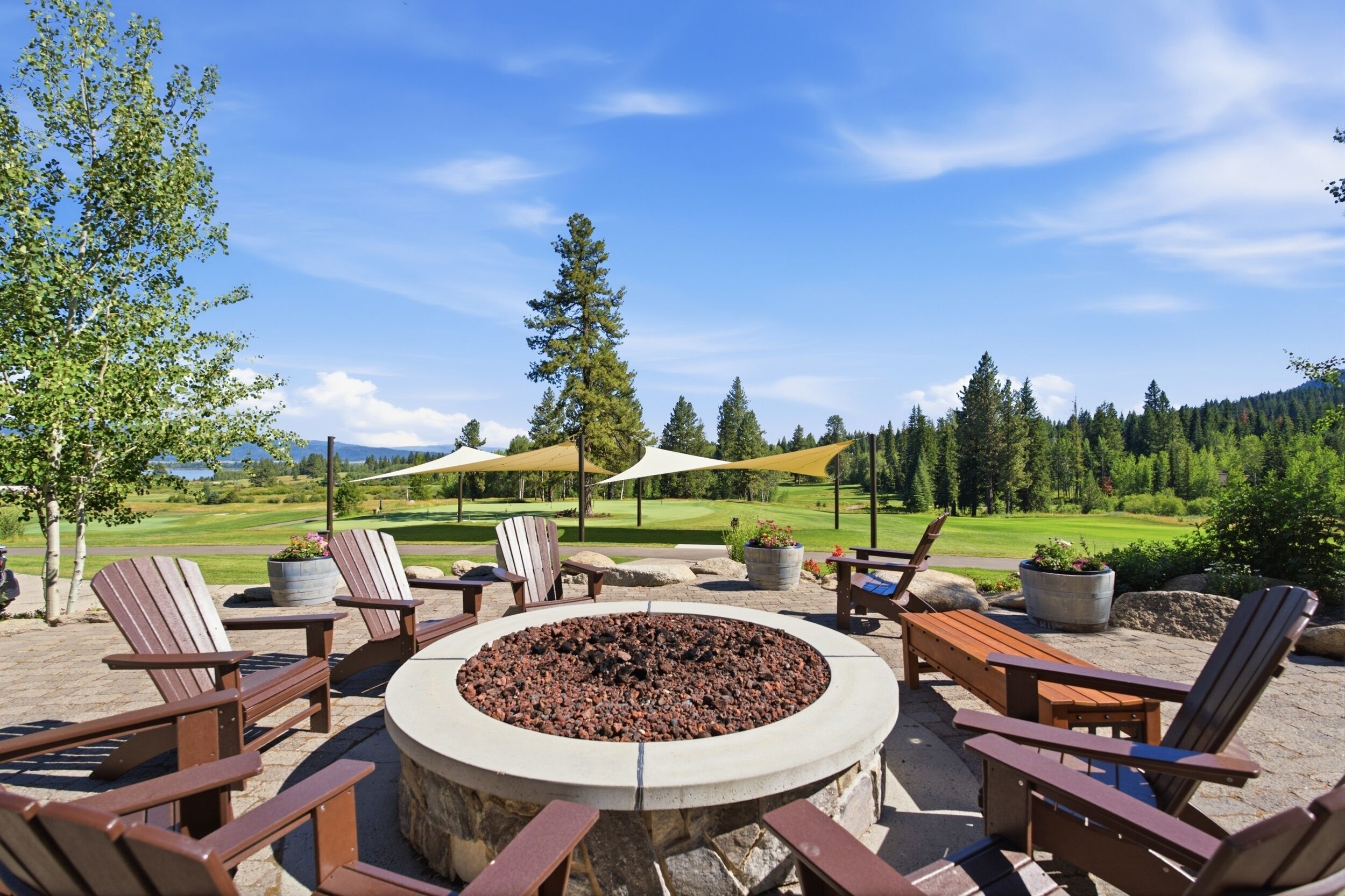 Un espace extérieur aménagé avec des chaises Adirondack, un foyer et une vue sur un terrain de golf.