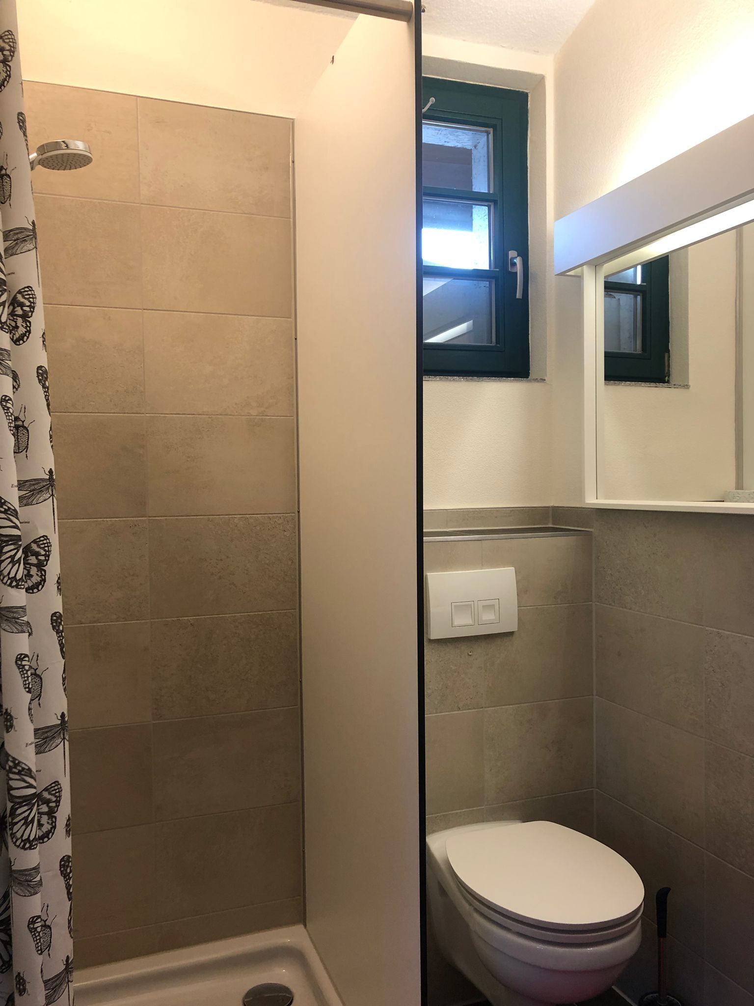 Ein Badezimmer mit Dusche, Toilette und einem Fenster.