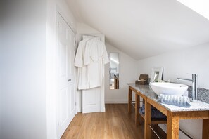 A modern bathroom with a wooden vanity, a white sink, and a mirror. - Elmbridge Farm Swallows Lodge (Droitwich)