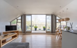 A spacious living area with a large window, wooden furniture, and a flat-screen TV. - Elmbridge Farm Swallows Lodge (Droitwich)