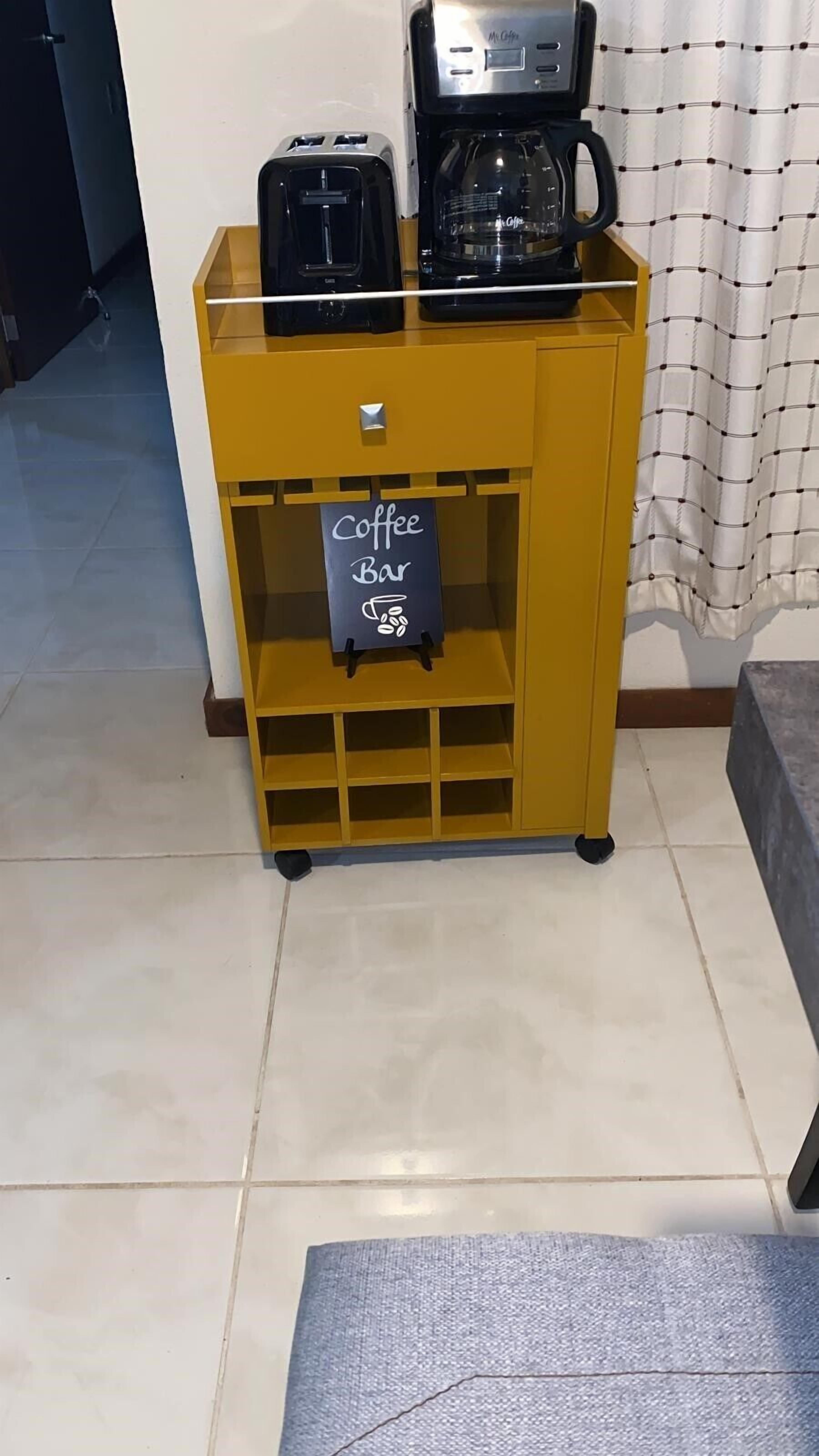 A yellow coffee station with a coffee maker and a sign that reads "Coffee Bar".