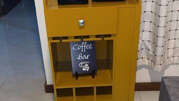 A yellow coffee station with a coffee maker and a sign that reads "Coffee Bar".