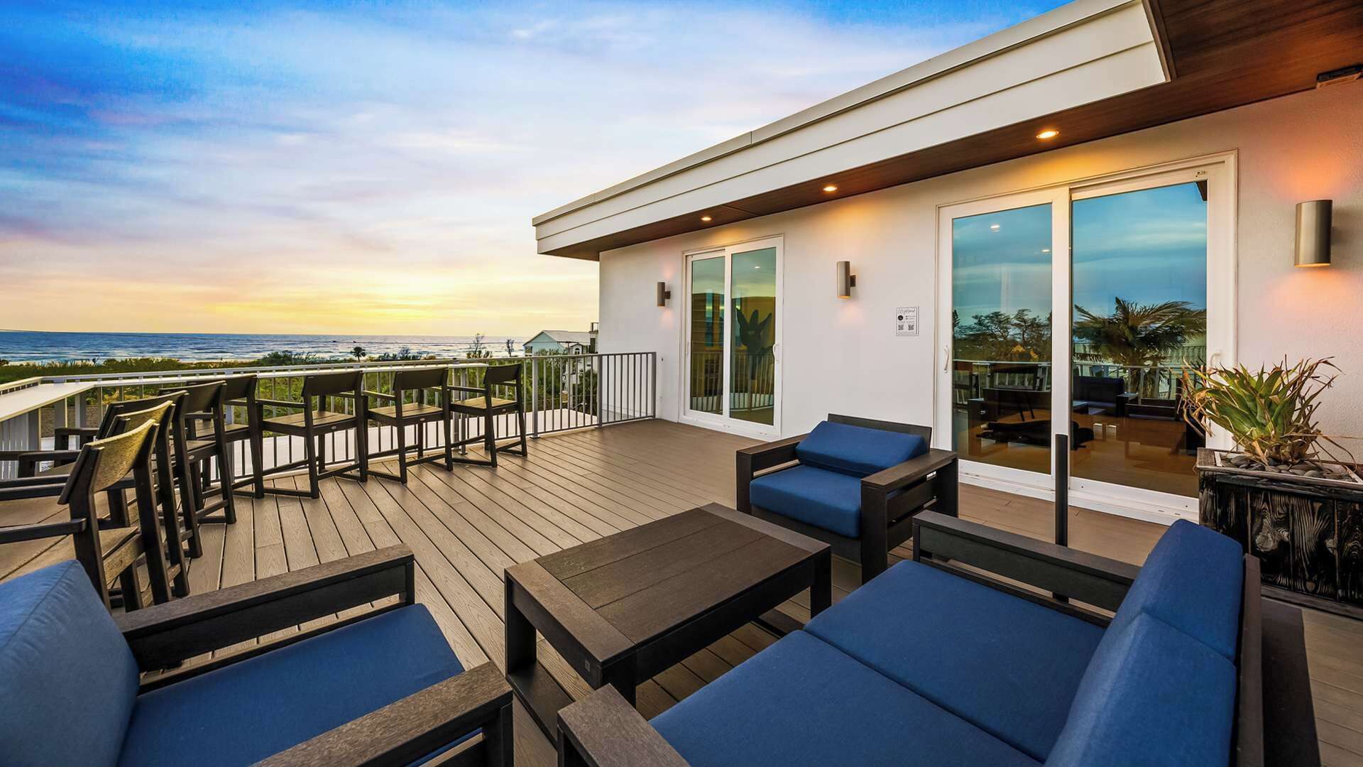 Une terrasse avec coin salon extérieur, un lit et une vue sur l’océan.