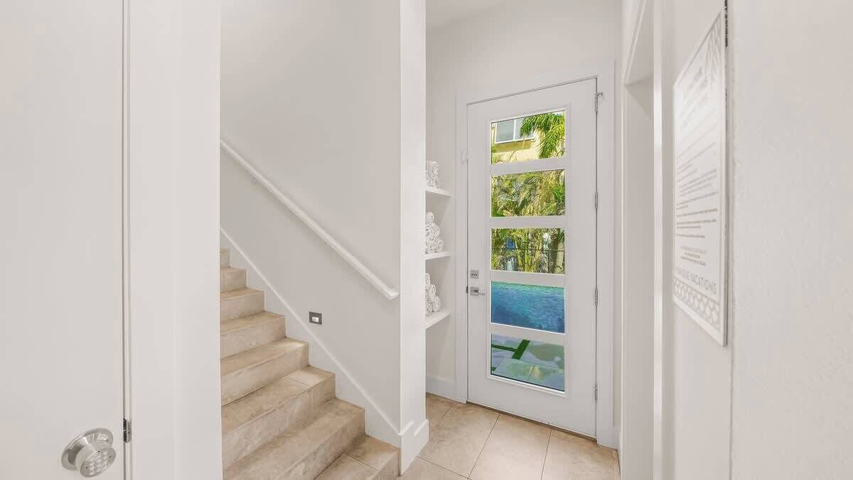 A staircase leading to a door with a glass panel, white walls, and a tiled floor.
