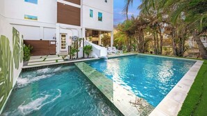A modern two-story building with a swimming pool, a covered outdoor area, and a staircase leading to the upper floor. - Steps to Beach/Gulf Views/Pool Volleyball/Slide (Siesta Key)