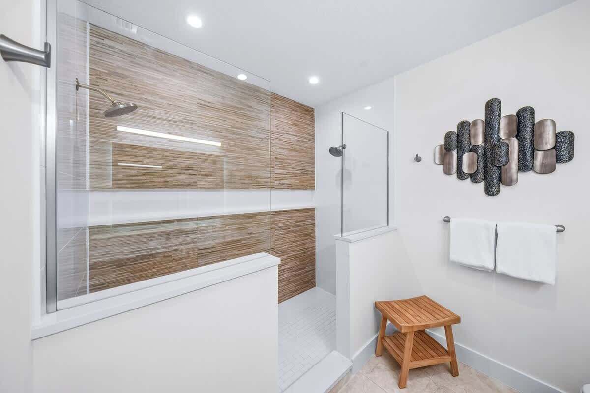 Une salle de bain moderne dotée d’une douche à parois de verre, d’un meuble-lavabo en bois et d’un porte-serviettes mural.