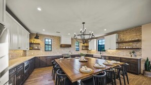 A spacious kitchen with a large island, dark cabinetry, and a chandelier. - Resort Pool w/Slide - Walk to Beach & Village (Sarasota)