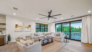 A spacious living room with a large window, a ceiling fan, and a view of the outdoors. - Resort Pool w/Slide - Walk to Beach & Village (Sarasota)