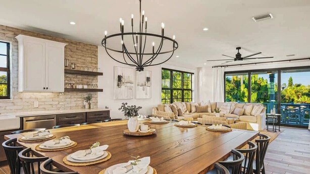 A spacious kitchen with a large wooden table set for dining, a chandelier, and a view of the outdoors. - Resort Pool w/Slide - Walk to Beach & Village (Sarasota)