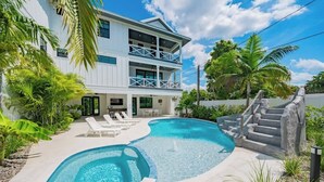 A two-story house with a swimming pool, outdoor furniture, and tropical plants. - Resort Pool w/Slide - Walk to Beach & Village (Sarasota)
