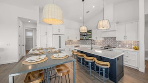 A modern kitchen with white cabinets, a central island with bar stools, and pendant lighting. - Steps to Beach/Pool w/Slide and Chipping Green (Sarasota)