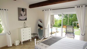 Une chambre à coucher avec un lit, une commode, un miroir et une fenêtre avec des rideaux.