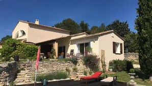 Une maison avec une piscine, des murs en pierre et un espace salon extérieur.