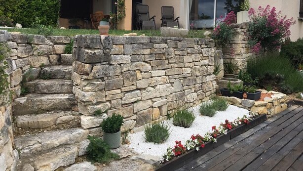 Une maison avec un escalier en pierre menant à un patio couvert.