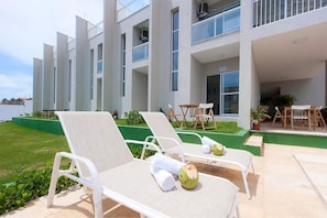 A modern hotel with white lounge chairs and a pool area. - Casa em Porto das Dunas por Carpediem (Aquiraz)